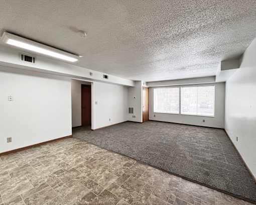 A spacious room with a carpeted floor and large windows.