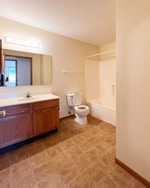 A bathroom with a toilet, sink, and mirror.