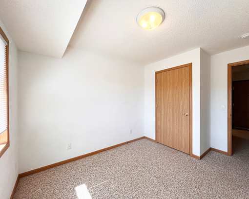 A room with a carpeted floor and a wooden door.
