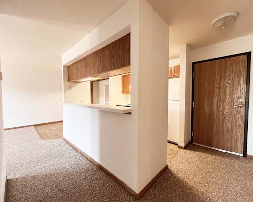 A white kitchen with a brown counter top and a brown door.