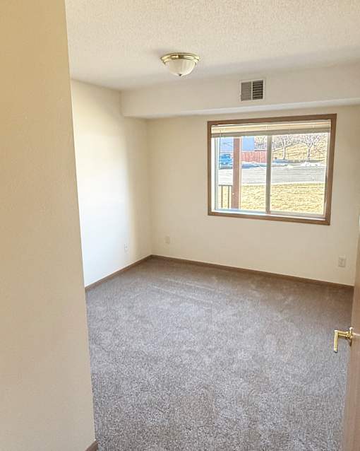 A room with a carpeted floor and a window.