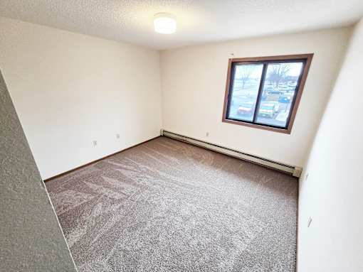 A room with a carpeted floor and a window.