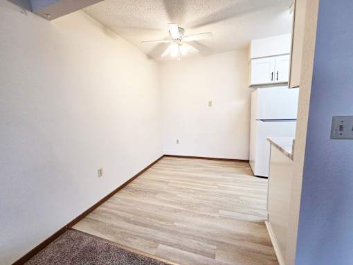 A room with a ceiling fan and a white cabinet.