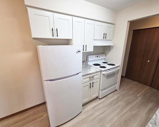 A small kitchen with a white fridge and a white stove top oven.