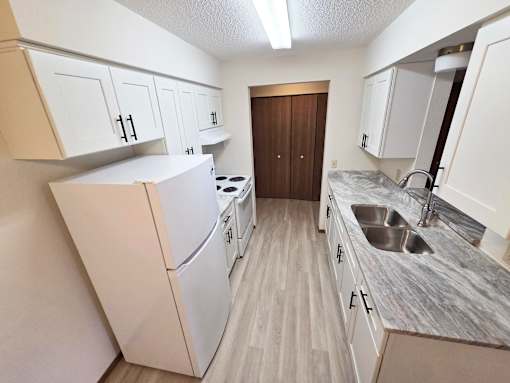 A kitchen with white cabinets and a marble countertop.