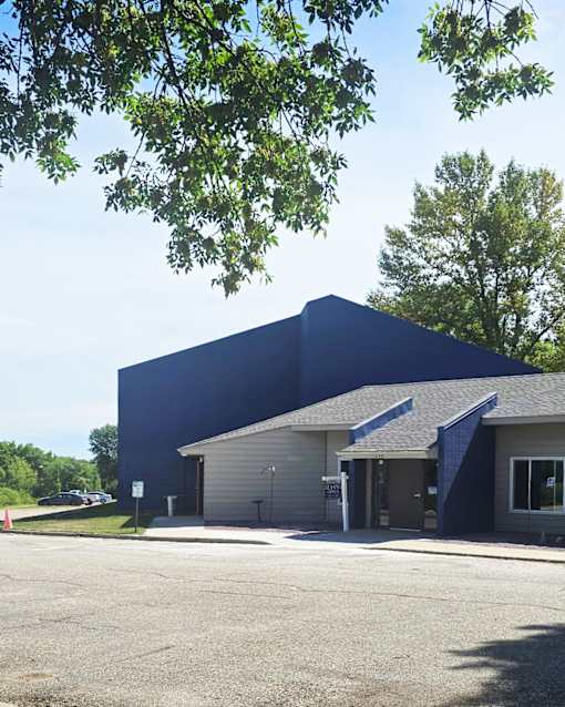 A blue building with a parking lot in front.