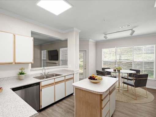 An open kitchen with a stainless steel dishwasher, white cabinets, a kitchen island next to a dining area with large windows. at Crescent Apartment Homes, Lenexa, KS