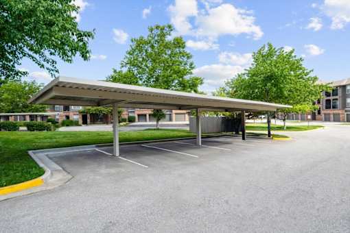 A parking lot with a covered parking area and trees in the background. at Crescent Apartment Homes, Lenexa, 66219