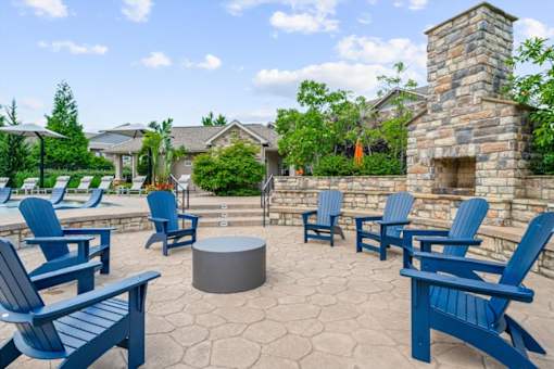 A patio with blue chairs and a fireplace at Stonepost Crossing Apartments, KS, 66213