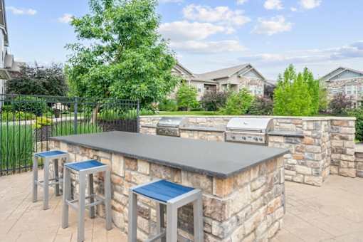 A barbecue grill is on a stone patio at Stonepost Crossing Apartments, Overland Park