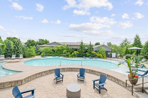 A pool surrounded by blue chairs and a stone patio at Stonepost Crossing Apartments, Overland Park, KS