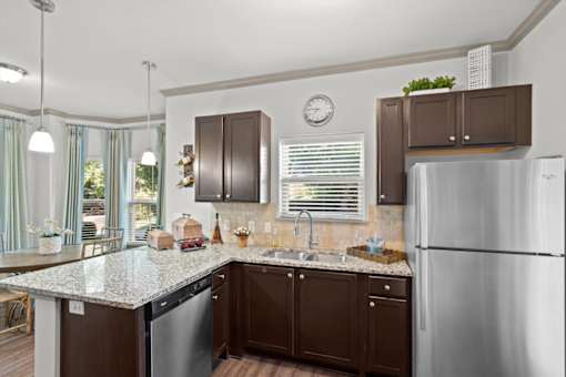 a kitchen with brown cabinets and a granite counter top at Stonepost Crossing Apartments, Kansas, 66213