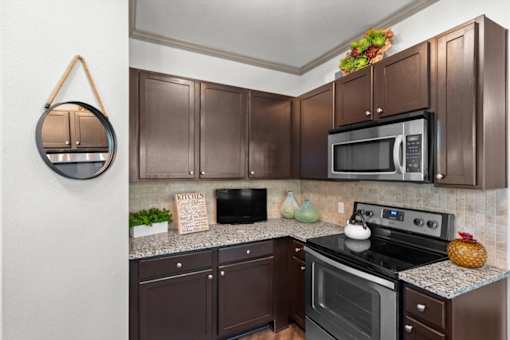 a kitchen with dark cabinets and stainless steel appliances at Stonepost Crossing Apartments, Overland Park, Kansas