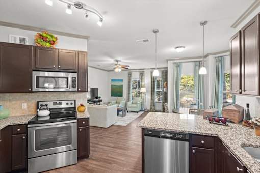 a kitchen and living room with wood floors and a ceiling fan at Stonepost Crossing Apartments, Overland Park, 66213