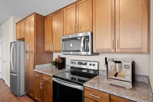 a kitchen with a stove top oven next to a refrigerator at The Dorset, Kansas City, 64112