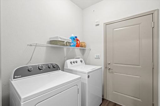 a laundry room with a washer and dryer next to a door at Stonepost Crossing Apartments, Overland Park, 66213