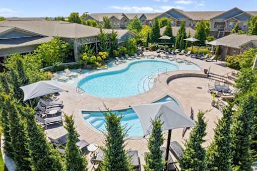 an aerial view of a resort style pool with chaise lounge chairs and umbrellas at Stonepost Crossing Apartments, Overland Park, Kansas