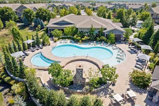 an aerial view of a resort style pool with chaise lounge chairs and umbrellas at Stonepost Crossing Apartments, Overland Park, Kansas