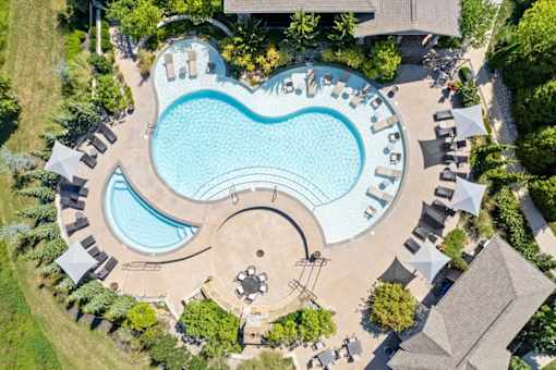 an aerial view of a swimming pool with lounge chairs and trees at Stonepost Crossing Apartments, Overland Park, 66213
