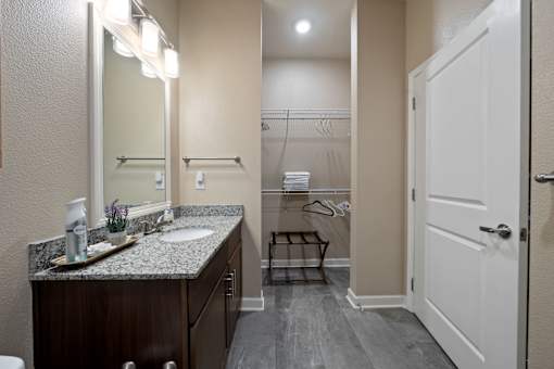 A bathroom with a sink, mirror, and towel rack.