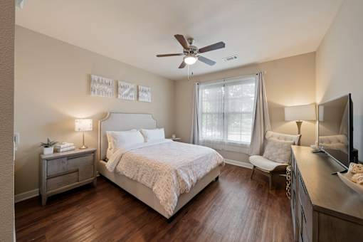 Guest suite bedroom at The Dorset featuring a queen bed, nightstand, window with natural light, and wood-style flooring