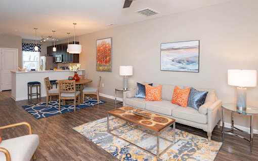 A living room with a white couch, a wooden coffee table, and a painting on the wall.