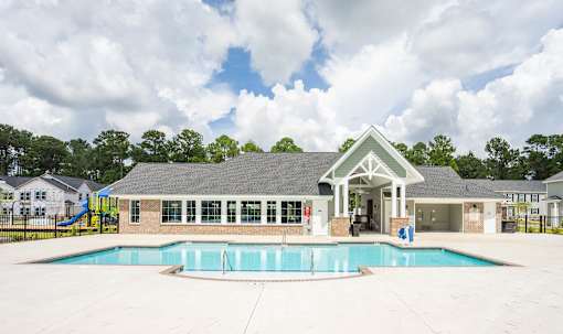 A pool area with a building and a slide in the background.