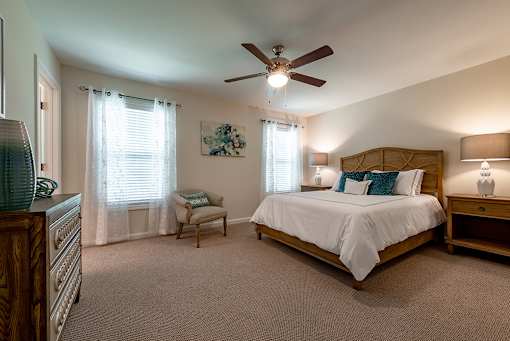 A bedroom with a large bed and a ceiling fan.