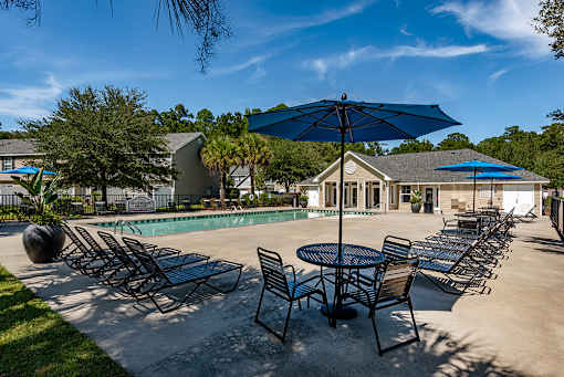 A sunny day at the poolside with chairs and umbrellas.