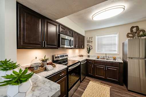 A kitchen with dark brown cabinets and a white countertop.