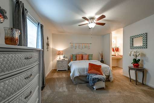 A bedroom with a bed, dresser, and ceiling fan.
