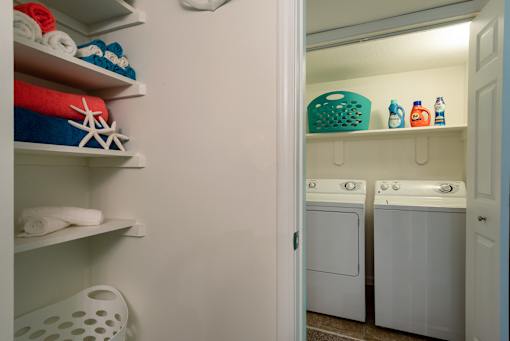 A laundry room with a washer and dryer connections and linen closet