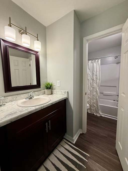 A bathroom with a sink, mirror, and a striped rug.