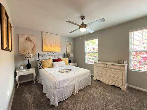 A bedroom with a bed, dresser, and ceiling fan.
