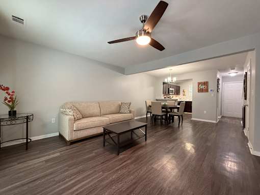 A living room with a beige couch, a coffee table, and a ceiling fan.