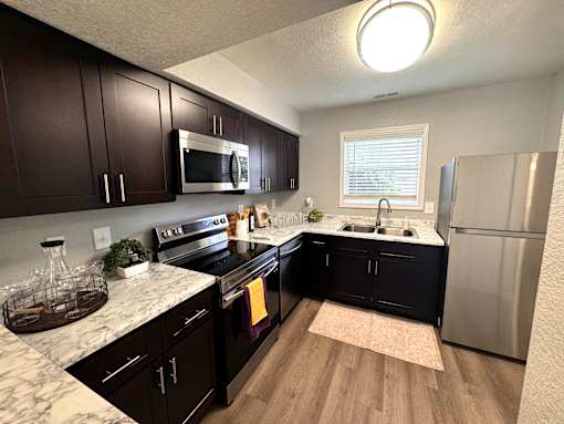 A kitchen with dark wood cabinets and a marble countertop.