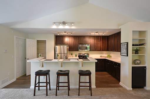 A kitchen with a white island and bar stools.