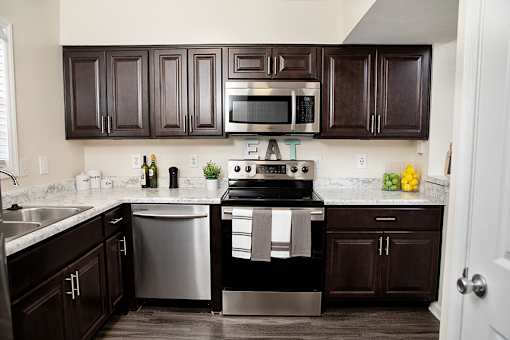 A kitchen with dark brown cabinets and a black stove top oven.