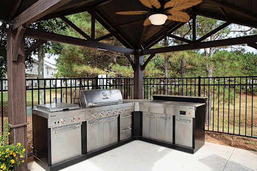 A BBQ grill set up under a wooden pavilion.