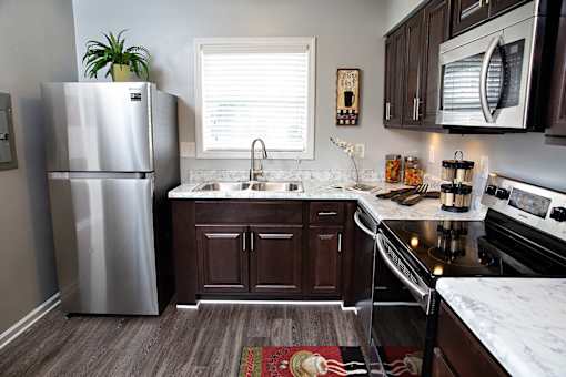 A kitchen with a stainless steel refrigerator and dark brown cabinets.