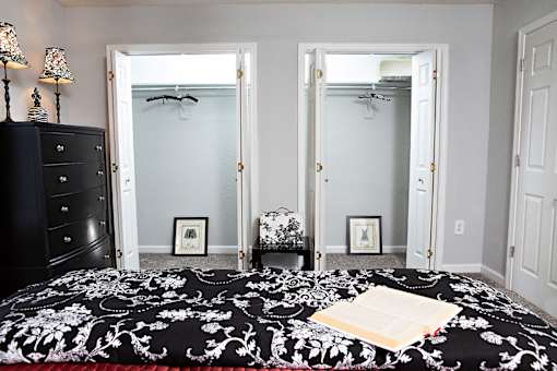 A bedroom with a black and white bedspread and a black dresser.