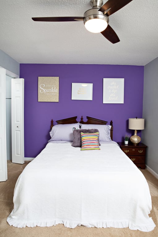 a bedroom with a white bed and a purple wall