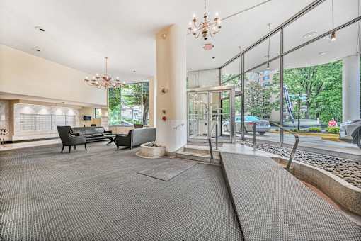 A large, open lobby with a grey carpet and a chandelier hanging from the ceiling.