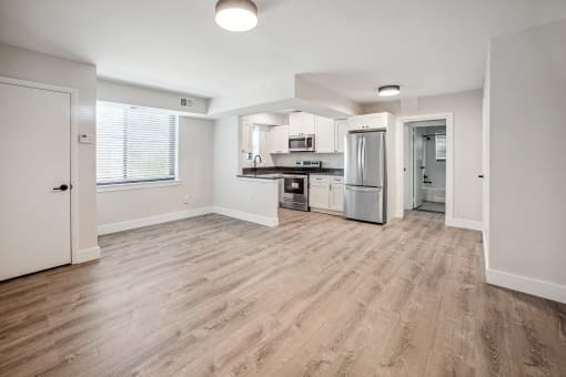 an empty kitchen and living room with hardwood flooring and white walls
