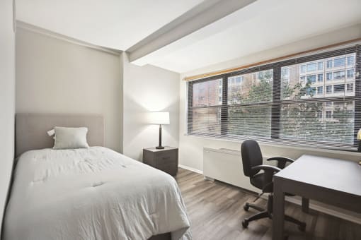 a bedroom with a bed and a desk and a large window