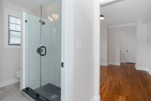a bathroom with a glass shower and a wooden floor