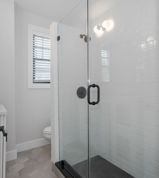 a white bathroom with a glass shower door
