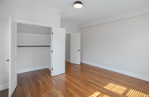 an empty living room with wood flooring and an open closet