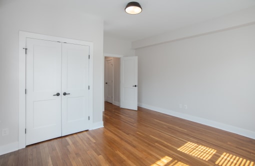 an empty living room with white doors and wood flooring