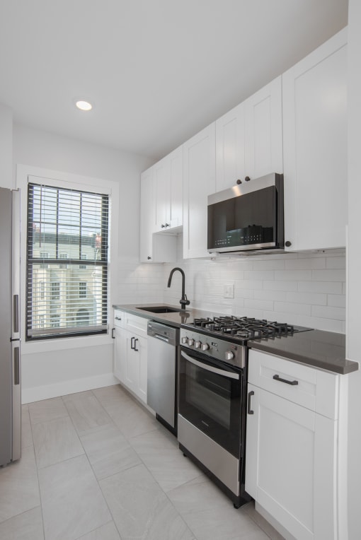 a kitchen with white cabinets and a stove and a window